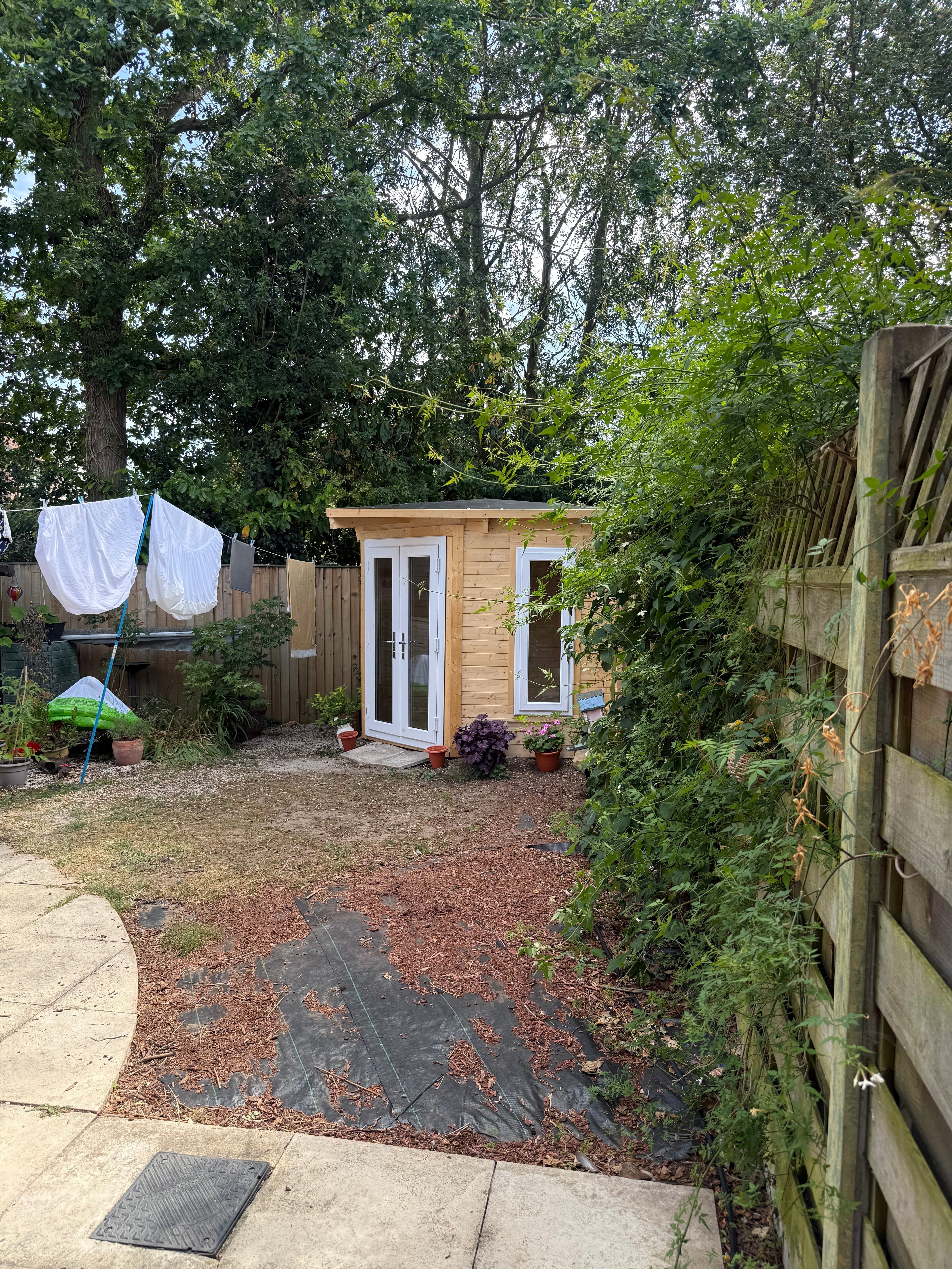 Dunster House corner log cabin fully installed in York garden — complete exterior view with French doors, side window and EPDM rubber roof