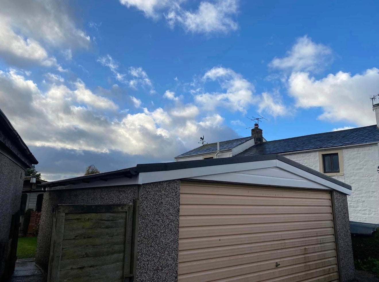 Completed garage roof replacement in Cockerham Lancashire — new timber apex roof with EPDM rubber membrane, white uPVC fascias and black gutters on pebbledash garage