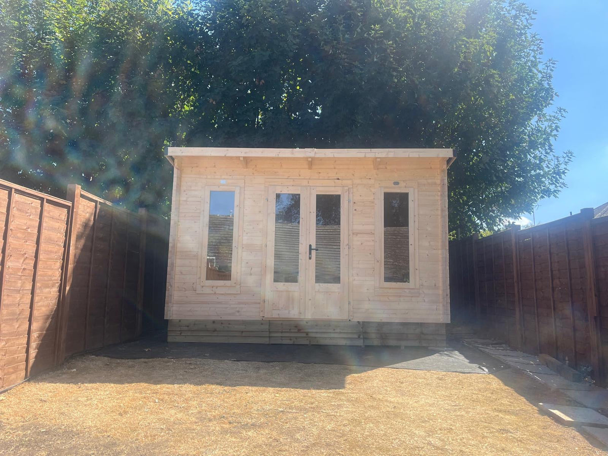 Completed timber garden cabin in Weybridge, Surrey, with glazed double doors and tall front windows